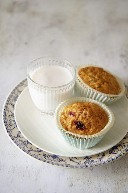 Muffins with raisins next to a glass of milk — Stock Photo