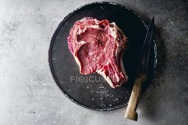 Raw beef steak with a knife on metallic background — Stock Photo