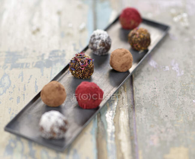 Fecha de chocolate y bolas de nuez con cacao, coco, pétalos secos y fruta en polvo - foto de stock