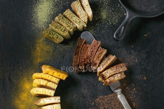Нарезанные оладьи с чаем маття, куркума и какао порошок с ножом и сковородкой — стоковое фото