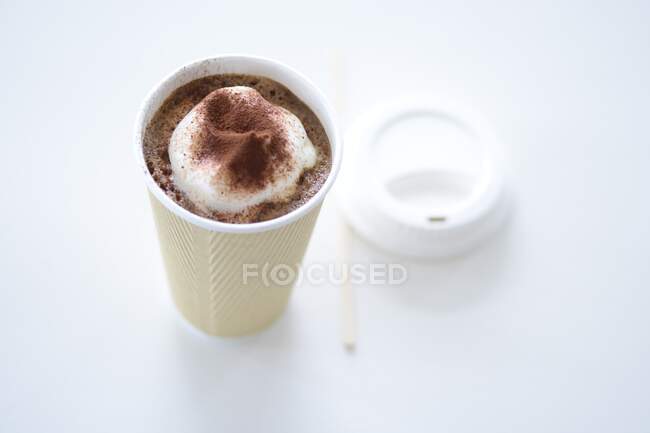 Una taza de cacao con crema en una taza para llevar - foto de stock