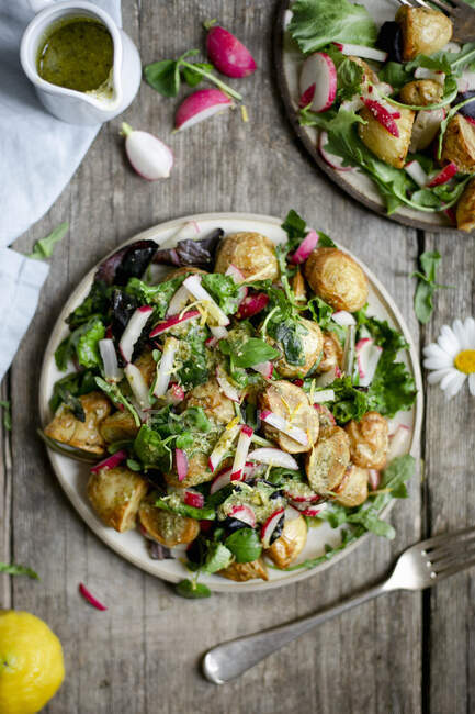 Roasted potatoes salad with chopped radish and green pesto on wooden backdrop — Stock Photo