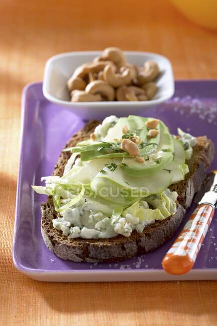 Dark bread topped with Roquefort, apples, avocado and cashew nuts — Stock Photo