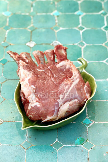 A raw rack of lamb in a leaf shaped bowl — Stock Photo