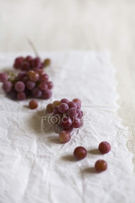 Uvas vermelhas frescas em papel — Fotografia de Stock