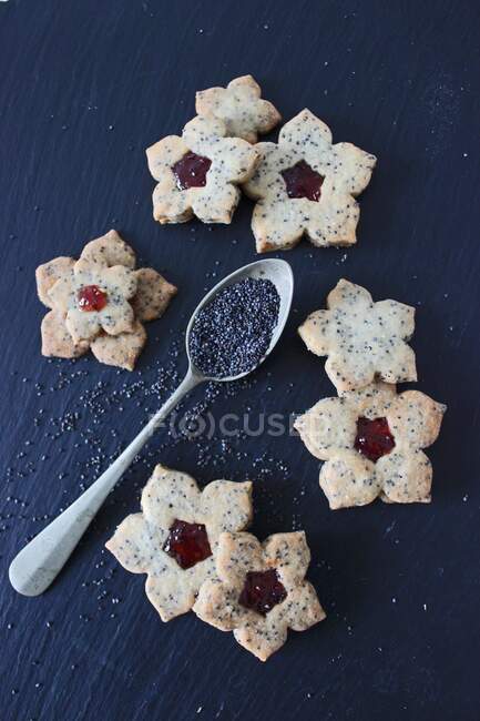 Cucchiaio con semi di papavero, biscotti con semi e marmellata sul tavolo — Foto stock