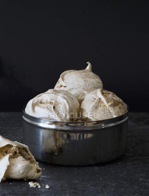Metal bowl with big meringues sifted with cocoa — Stock Photo