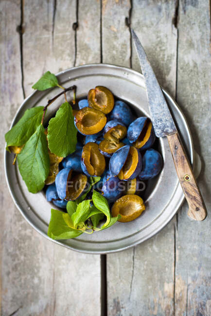 Damsons with leaves on a pewter plate — Stock Photo