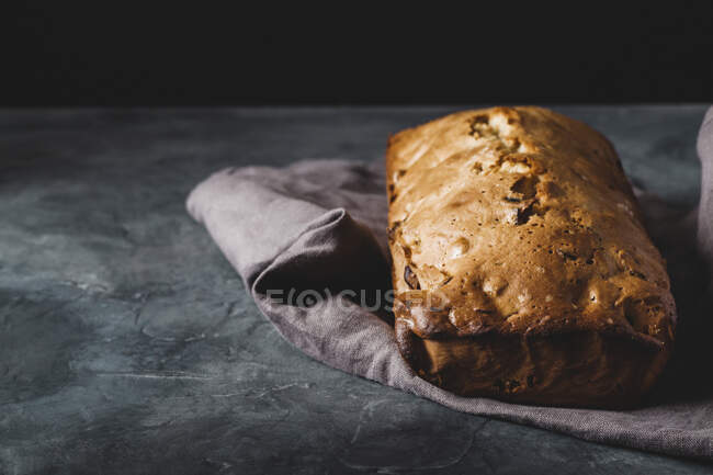 Fruit loaf on a linen cloth on a dark stone surface — Stock Photo