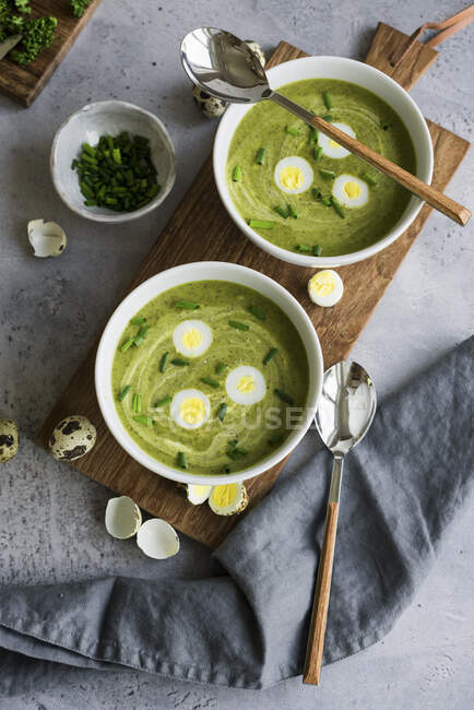Традиционный франкфуртский зеленый травяной суп с перепелиными яйцами и луком в мисках на деревянной доске — стоковое фото