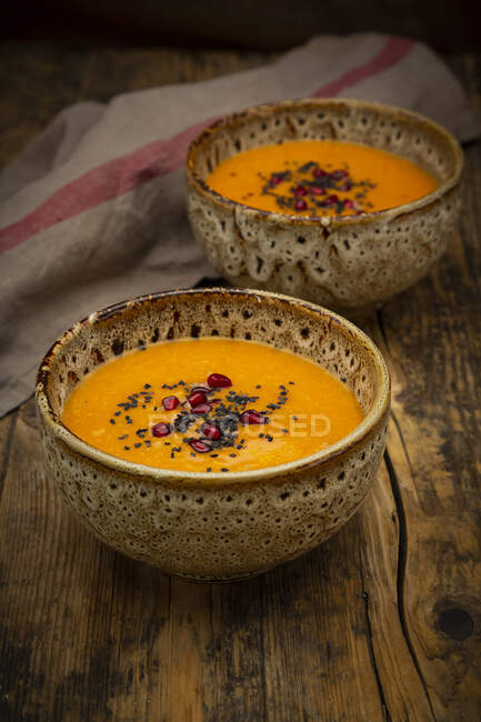 Oriental carrot, ginger and coconut soup with black sesame seeds and pomegranate seeds — Stock Photo