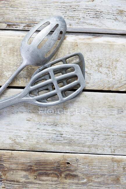 Three old metal spatulas on a wooden background — Stock Photo