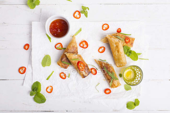 Spicy spring rolls served with fresh chili peppers, fresh mint and spicy sauce — Stock Photo