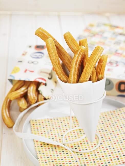 Churros in a paper cone to take away — Stock Photo