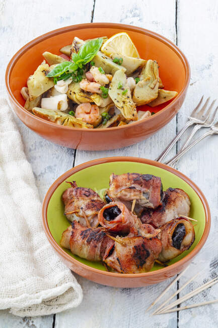 Tapas: artichoke salad and prunes wrapped in bacon — Stock Photo