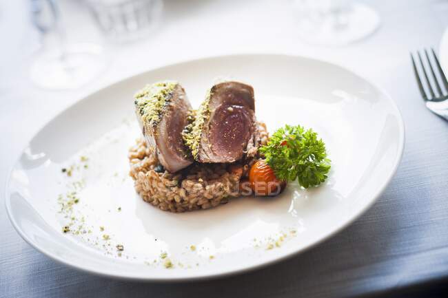 Tuna in pistachios crust on bed of spelt and vegetables — Stock Photo