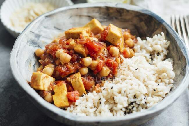 Curry vegano con garbanzos y tofu, servido con arroz integral - foto de stock