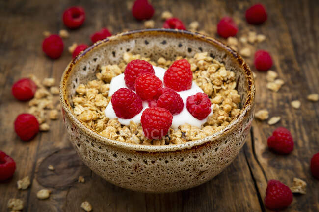 Granola con yogur y frambuesas en tazón de cerámica - foto de stock