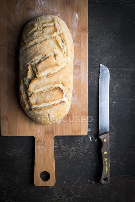 Pane fatto a mano su tavola di legno con coltello alla superficie scura — Foto stock