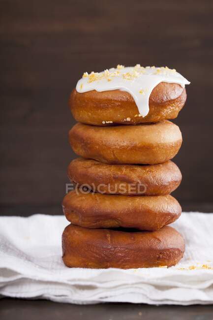 Donuts com um esmalte de limão e pedaços de laranja cristalizados, empilhados — Fotografia de Stock