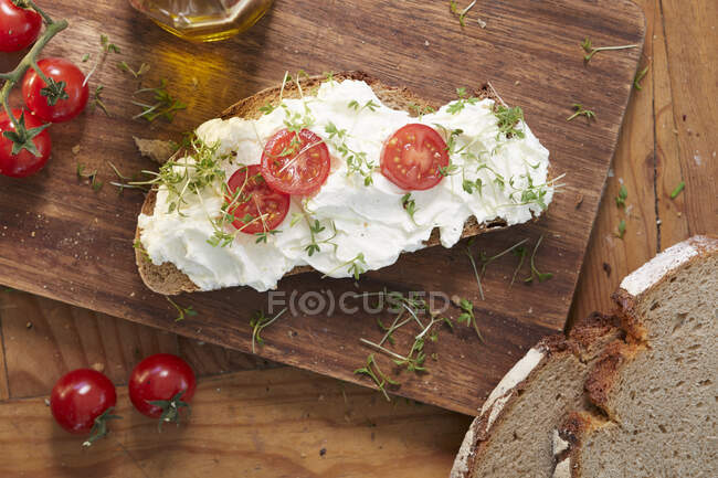 Fatia de pão coberto com creme de queijo, tomate e agrião — Fotografia de Stock