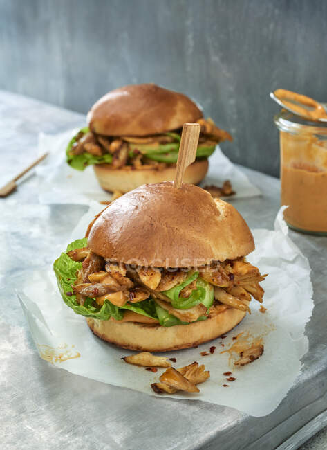Two pulled chicken burgers on parchment paper — Stock Photo