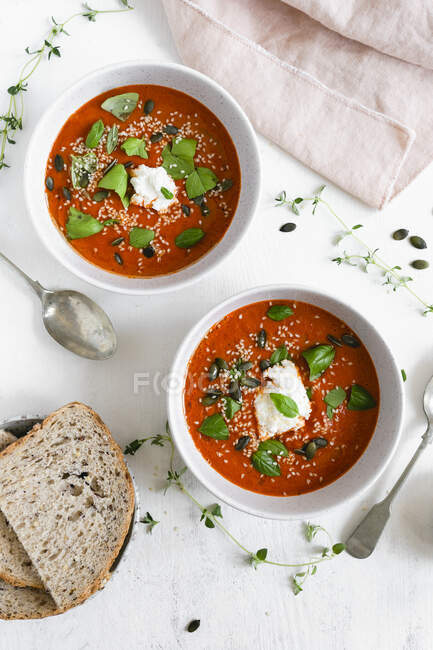 Deux bols de soupe de tomates rôties garnis de basilic frais et de fromage ricotta — Photo de stock