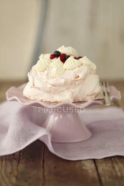 Розовый безе торт с ягодами на стенде — стоковое фото