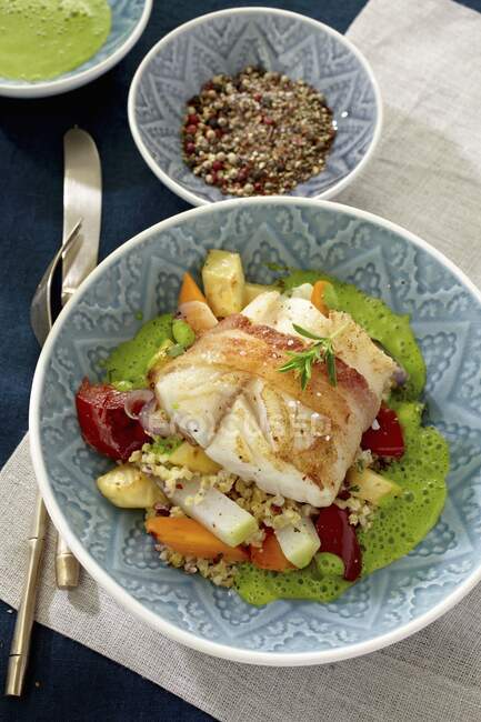 Cod wrapped in bacon on bed of vegetables and couscous with green sauce — Stock Photo