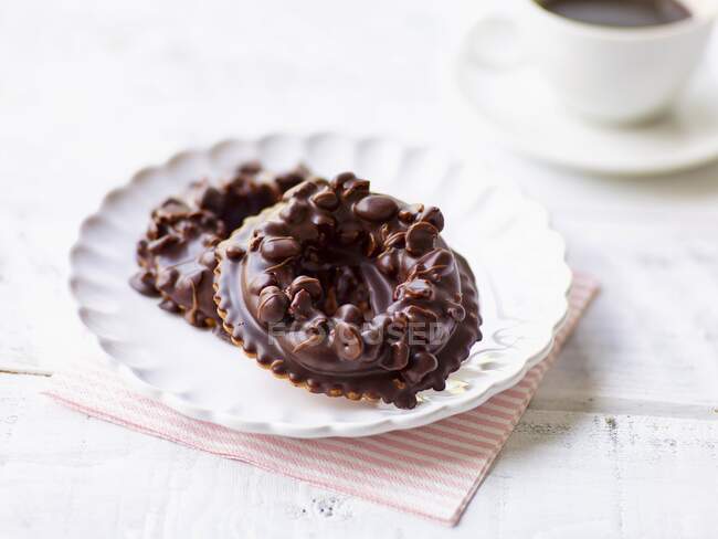 Avelãs e anéis de nougat cobertos de chocolate no prato de sobremesa — Fotografia de Stock