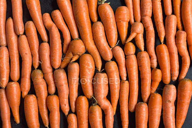 Zanahorias sobre una superficie negra - foto de stock