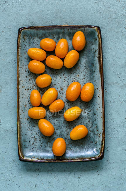 Kumquats on a blue craft plate — Stock Photo