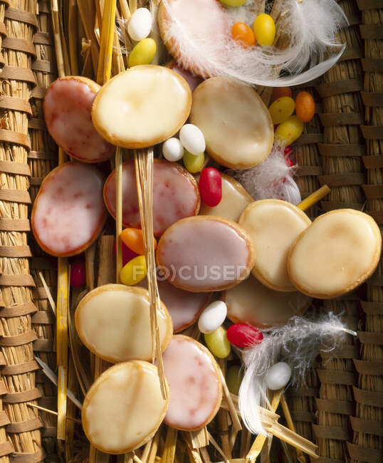 Galletas glaseadas de limón y frambuesa en cesta con plumas para Pascua - foto de stock