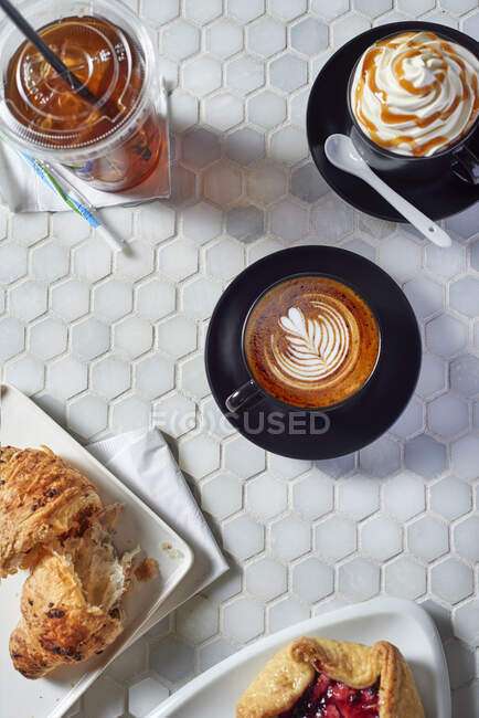 Різні кавові напої та солодка випічка на столі в кавовому барі — стокове фото