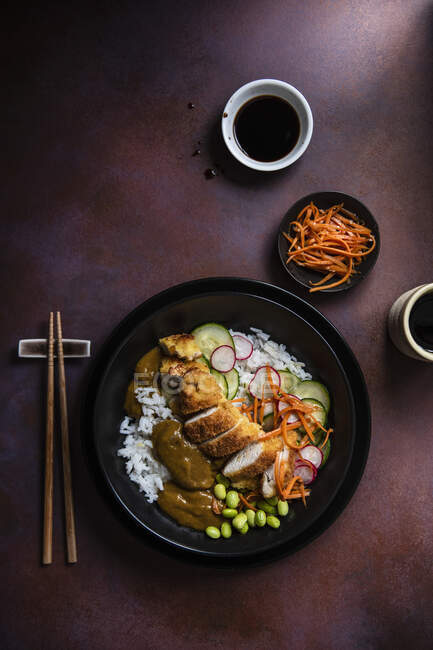 Pollo katsu japonés con pepino en escabeche, zanahorias en aceite de sésamo y judías de edame - foto de stock