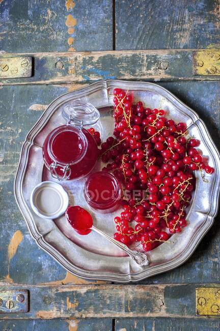 Красная смородина варенье в стеклянных банках и свежие ягоды на металлической пластине — стоковое фото