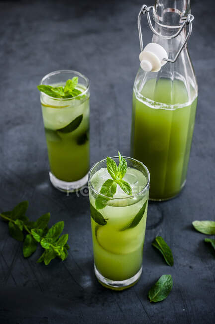 Bevanda alcolica al cetriolo e menta in bottiglia e bicchieri — Foto stock