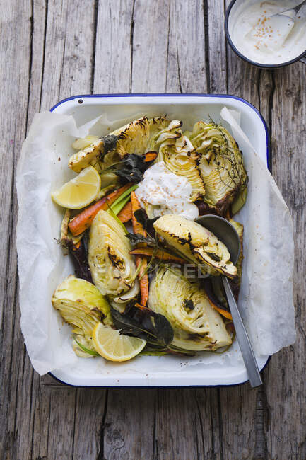 Roasted white cabbage in a baking dish with sage, carrots, lemon and a yoghurt dip — Stock Photo