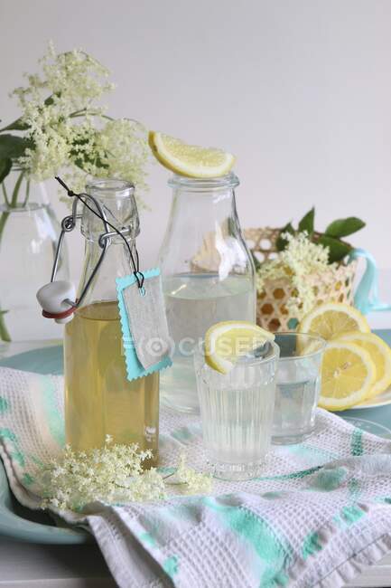 Xarope de flor de sabugueiro em uma garrafa e despejado em copos com fatias de limão — Fotografia de Stock