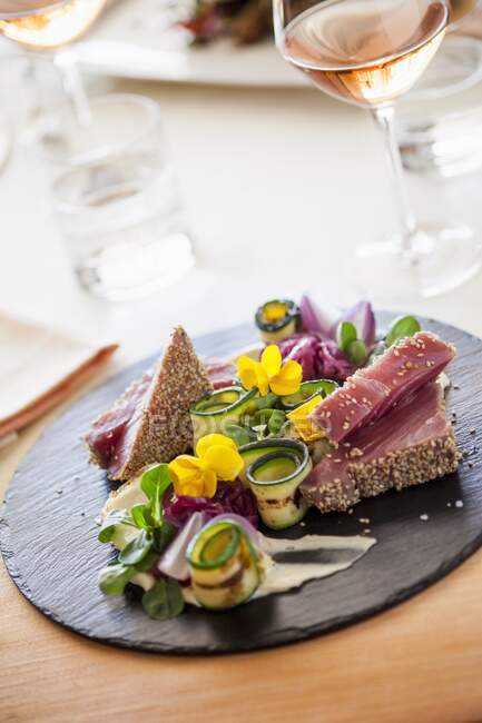 Tuna in sesame crust with grilled zucchini and salad leaves — Stock Photo