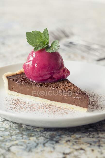 A slice of chocolate tart with raspberry sorbet — Stock Photo
