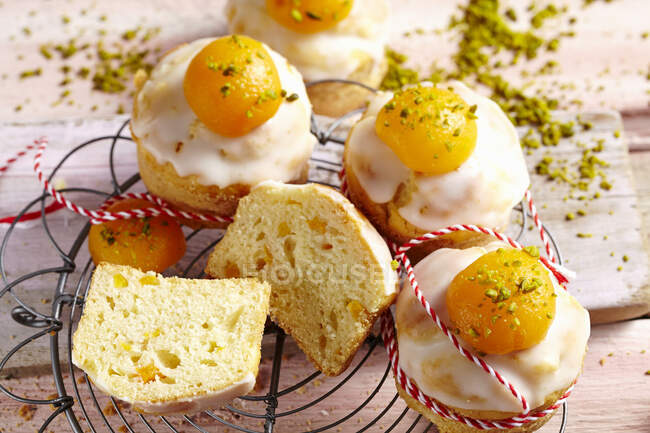 Muffins with icing, apricots and grated pistachios on wire rack — Stock Photo