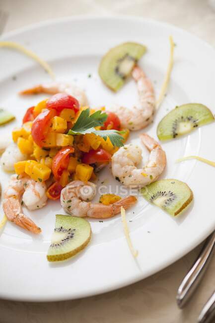 Shrimps with pumpkin cubes, cherry tomatoes and kiwi slices — Stock Photo