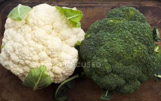 Cauliflower and broccoli on wood cutting board — Stock Photo