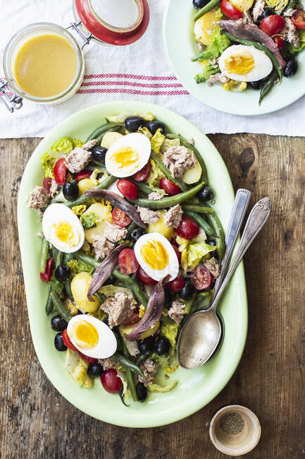Salad nicoise with romain lettuce, cherry tomatoes, tuna, green beans, black olives, anchovies and hard-boiled eggs — Stock Photo