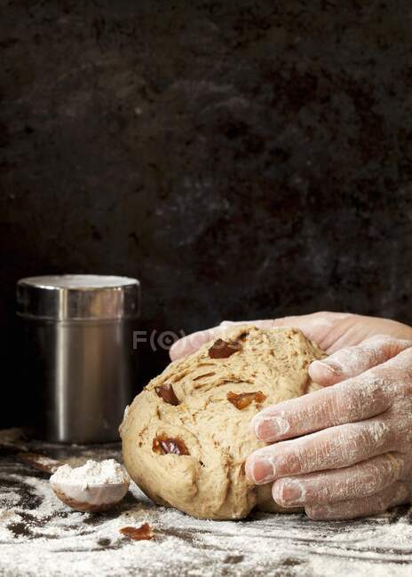 Hands shape rice bread dough with dates into a loaf — Stock Photo