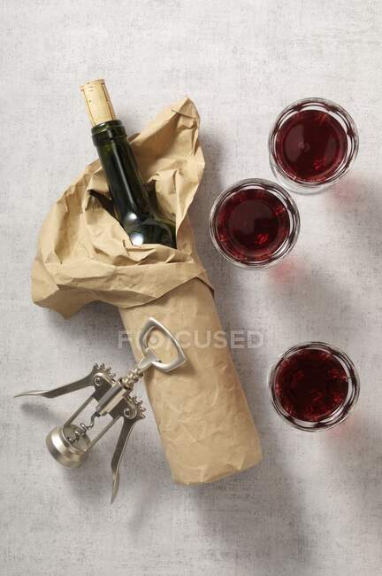Une bouteille de vin emballée, des verres de vin rouge et un tire-bouchon — Photo de stock