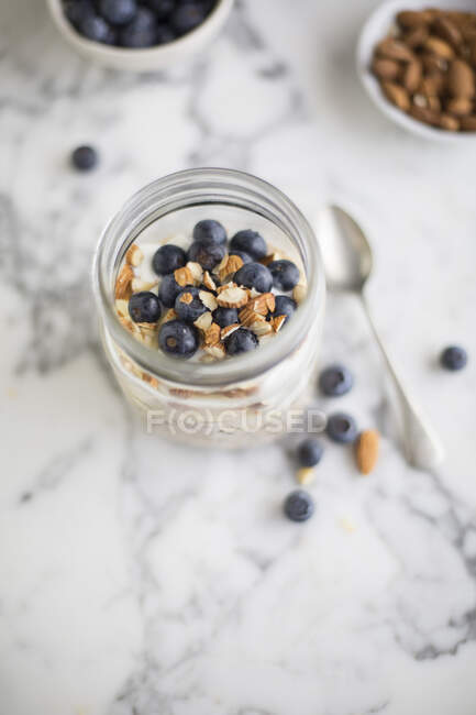 Overnight oats with blueberries and almonds in jar on marble surface — Stock Photo
