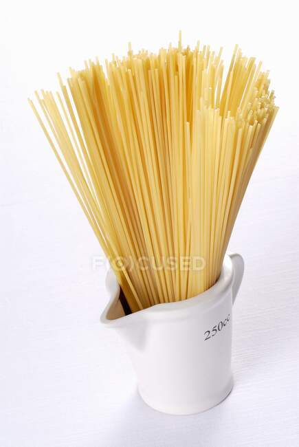 Primer plano de deliciosos espaguetis en una taza de medir - foto de stock