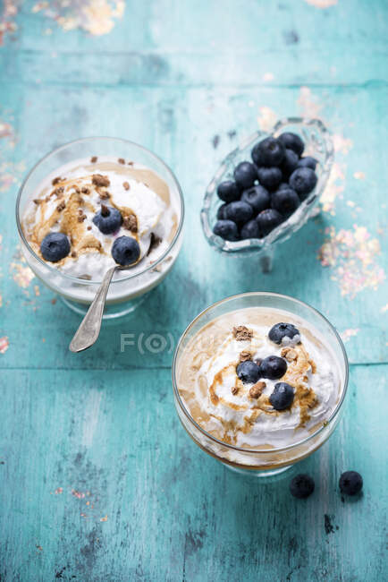 Pudding dessert with cream, caramel and fresh blueberries in glasses and mini bowl — Stock Photo
